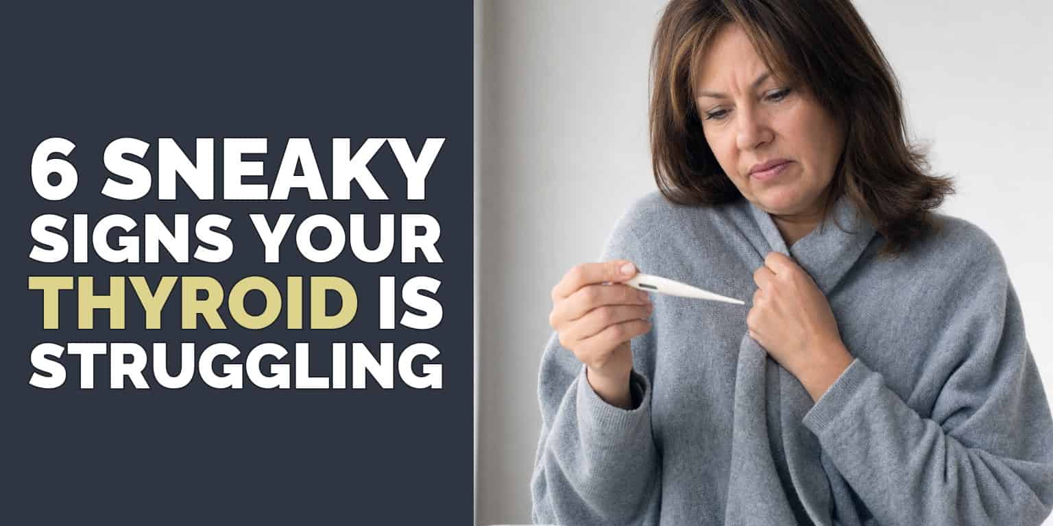 Woman in a grey cardigan checking a thermometer, a sign of the low body temperature caused by a thyroid problem